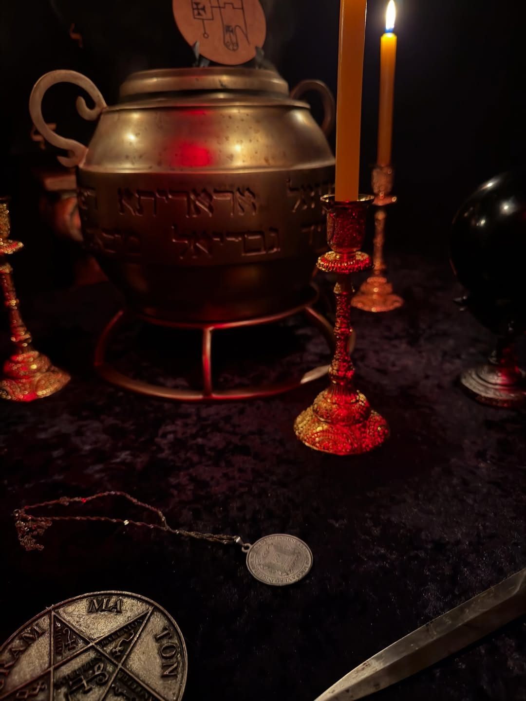 Altar com velas vermelhas, caldeirão e adaga sobre veludo vinho