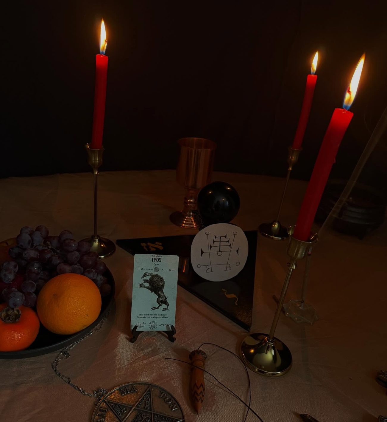 Altar com velas carmim, frutas e pentáculo do Tetragrammaton